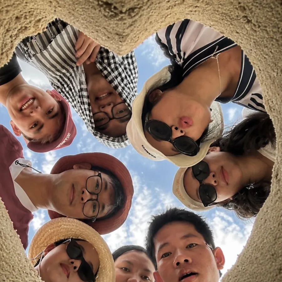 TechCoop colleagues looking down into a heart dug in the sand